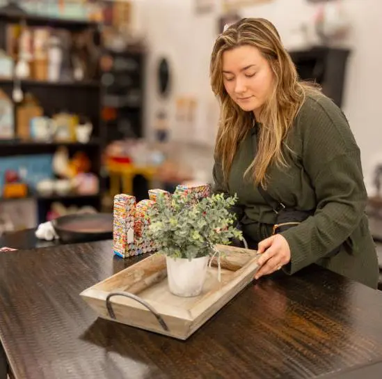 A woman is sitting at the table with a plant